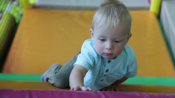Pojke klättrar på väggen med hinder i barnens nöjescentrum. Slow motion — Stockvideo