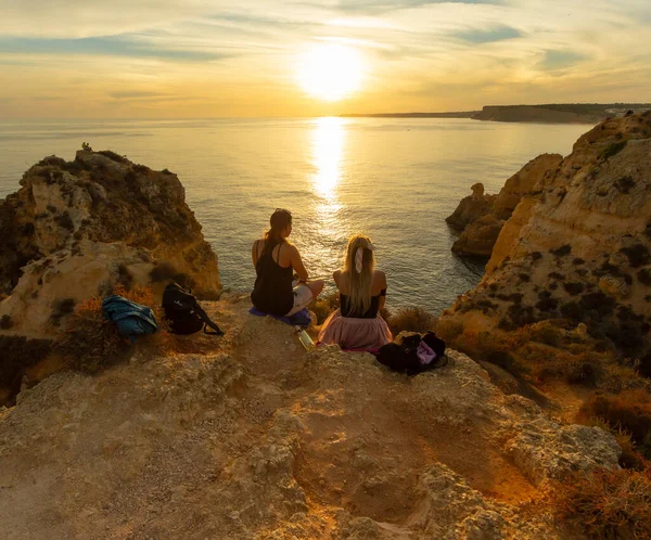 Ponta da Piedade, Lagos, Algarve, Portekiz 'de gün batımında içen iki kız..