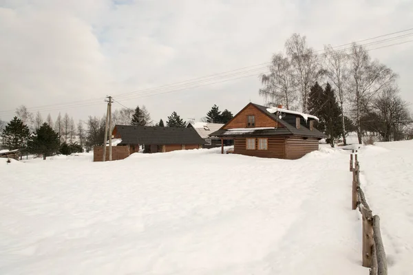Paisaje invernal con pocas casas de madera, nieve y cielo azul con nubes — Foto de Stock