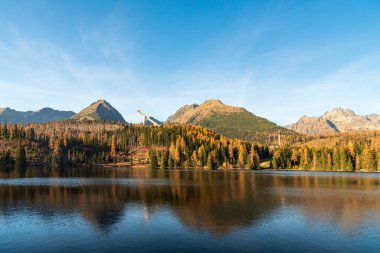 Slovakya 'daki Vysoke Tatry Dağları' nın sonbaharında, arka planda antik ormanların zirveleriyle Strbske pleso dağı.