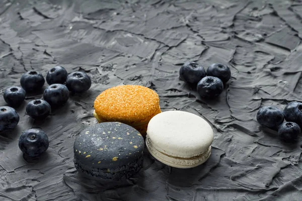 üç renkli macaroons ve yaban mersini gri bir arka plan üzerinde yalan