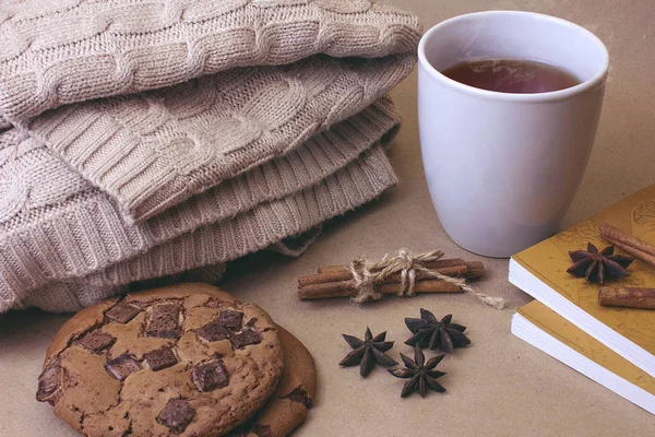 Sıcak çay Fincan, kurabiye ve örgü sıcak kış eşarp ve kahverengi Kraft arka plan kitaplar