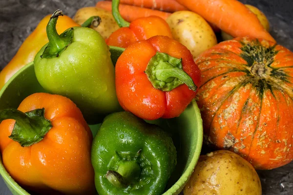 Gri bir arka plan üzerinde su damlaları ile üç olgun kırmızı biber