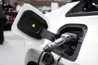 Elektrikli araba şarjı. EV şarj cihazı takıldı. Sürdürülebilir ulaşım ve yeşil teknoloji, artan elektrik hareketliliği eğilimini vurguluyor. Otomotiv yeniliği ile ilgili içerik için ideal.