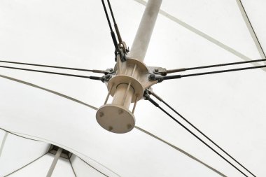 Kumaş paneller ve destekleyici kablolar tarafından oluşturulan geometrik çizgileri vurgulayan modern bir tuval çatı yapısı. mimari kavramlar, mühendislik, soyut arkaplanlar ve tasarımlar.