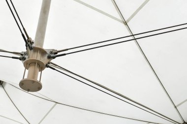 Kumaş paneller ve destekleyici kablolar tarafından oluşturulan geometrik çizgileri vurgulayan modern bir tuval çatı yapısı. mimari kavramlar, mühendislik, soyut arkaplanlar ve tasarımlar.