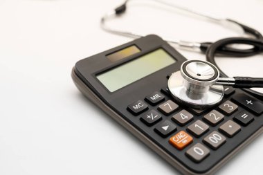 Hesap makinesi ve steteskop beyaz arka plan sağlık temalı fotokopi alanı. Sağlık giderleri veya sağlık sigortası.
