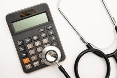 Hesap makinesi ve steteskop beyaz arka plan sağlık temalı fotokopi alanı. Sağlık giderleri veya sağlık sigortası.