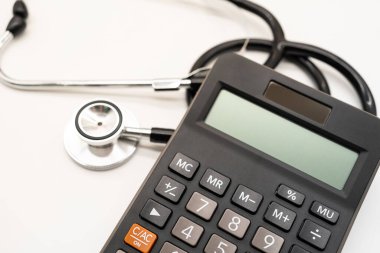 Hesap makinesi ve steteskop beyaz arka plan sağlık temalı fotokopi alanı. Sağlık giderleri veya sağlık sigortası.