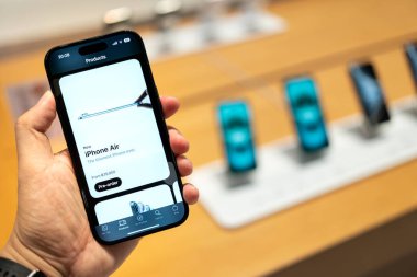 Eski bir iPhone modeliyle el ele tutuşmak, yeni iPhone Air 'in parlak tasarımını görüntülemek. iPhone Air Pro Ön Sipariş Ekranı Gösteriliyor.