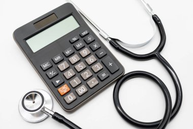 Fotokopi alanı olan beyaz arka plan sağlık temalı hesap makinesi ve steteskop. Sağlık giderleri veya sağlık sigortası.