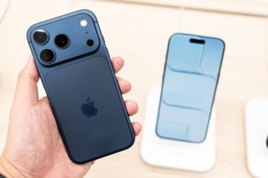 Hand holding a new iPhone 17 Pro Deep Blue  in a Store.