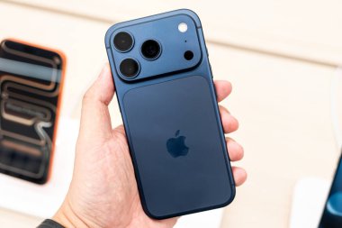 Hand holding a new iPhone 17 Pro Deep Blue  in a Store.