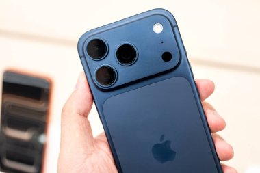 Hand holding a new iPhone 17 Pro Deep Blue  in a Store.