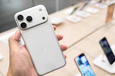 Hand holding a new iPhone 17 Pro Max Silver in a Store.