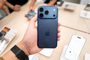 Hand holding a new Deep Blue iPhone 17 Pro Max in a Store.