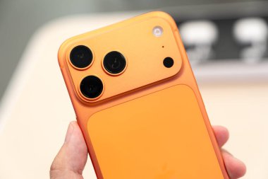 Hand holding a new Cosmic Orange iPhone 17 Pro Max in a Store.