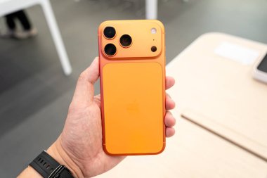 Hand holding a new Cosmic Orange iPhone 17 Pro Max in a Store.