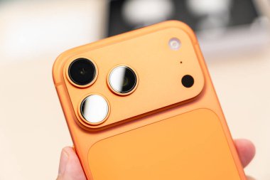 Hand holding a new Cosmic Orange iPhone 17 Pro Max in a Store.