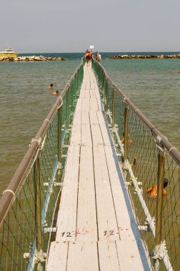 Paslanmaz çelik ve ahşap iskele, İtalya 'da Rimini yakınlarındaki Igea Marina' nın teknelerinde turist alımına olanak sağlıyor.