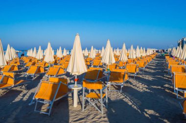 Rimini yakınlarındaki Igea Marina sahilinde turuncu şemsiyeler ve şezlonglar.