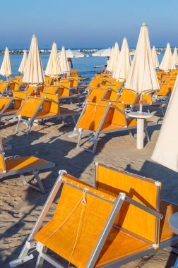 Rimini yakınlarındaki Igea Marina sahilinde turuncu şemsiyeler ve şezlonglar.