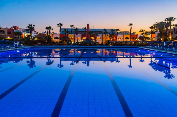 Vista di una piscina al tramonto con riflessi di palme — Foto Stock