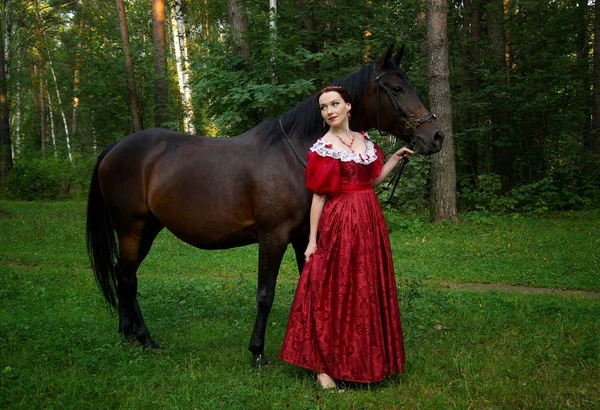 Vacker ung flicka i retro klänning posing nära häst — Stockfoto