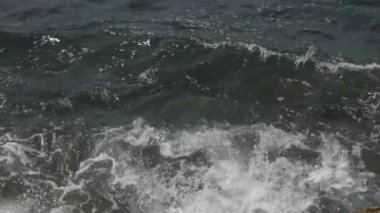 Güzel bir denizin mavi dalgalarının deniz kıyısındaki taşlara vuruşunu yakın çekim..