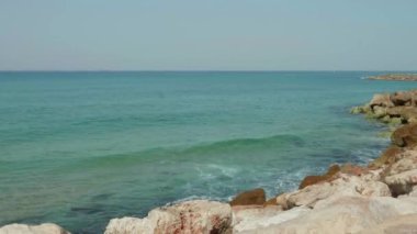 Deniz dalgaları yavaşça kayalık kıyıya çarpıyor. Geniş açı. Yavaş çekim 4K