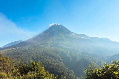 Sabah Merapi Dağı manzarası ve önü yemyeşil bir orman. Açık bir sabahta Merapi Dağı 'nın panoramik güzelliği belli bir mesafeden görülebiliyor..