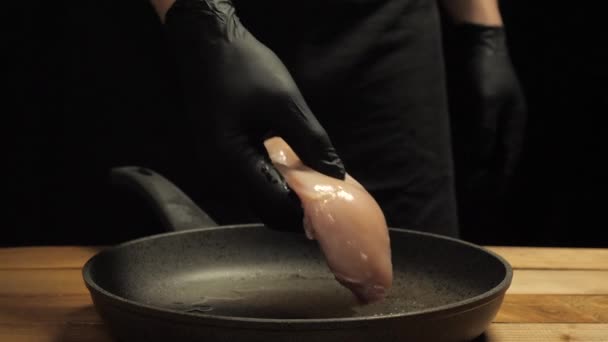 Cocinero pone guante filete de pollo en una sartén caliente — Vídeos de Stock