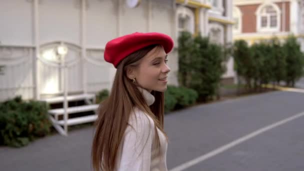 Дівчина гуляє по місту в червоному береті — стокове відео