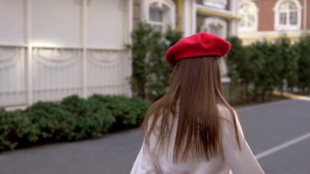 Ευτυχισμένο κορίτσι κυλά στην πόλη με ένα κόκκινο μπερέ — Αρχείο Βίντεο