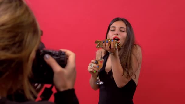 Model kız kamera bir fotoğrafçı konfeti üfleme ve elinde şampanya bir bardak ile poz — Stok video