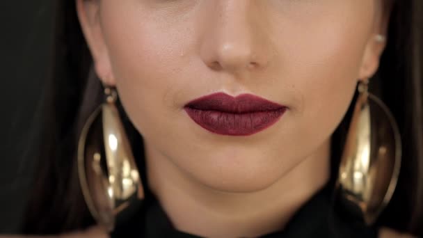 Meisje met Bourgondische lippenstift op haar lippen glimlachend op de camera. Close-up shot. Model met grote gouden oorringen — Stockvideo