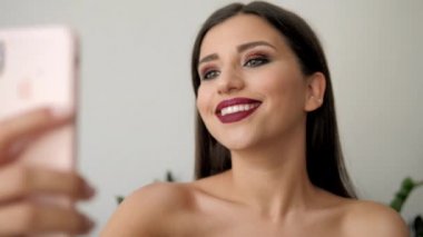 Parlak makyajlı esmer kız telefonda selfie yapıyor