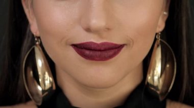 dudaklarında parlak ruj ile büyük altın küpe kız gülümseyerek. Yakın çekim