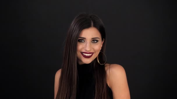 Brunette girl with holiday makeup is spinning in front of the camera on a black background — Stock Video
