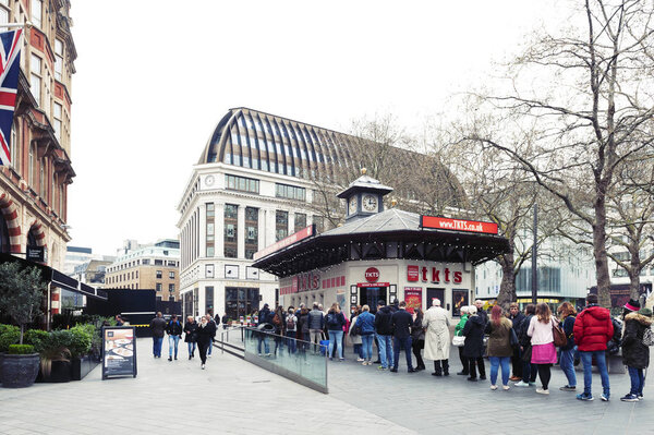 London, UK - April 2018: People queue for buying tickets from TKTS, the official London theatre ticket booth located at Leicester Square offering last minute and discount tickets for West End shows