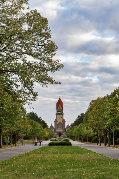 Leipzig, Germany - October 2018: Walkway in beautiful park toward chapel complex, bell tower, funeral hall, and crematorium of Leipzig South Cemetery in Leipzig, Germany — Stock Photo, Image