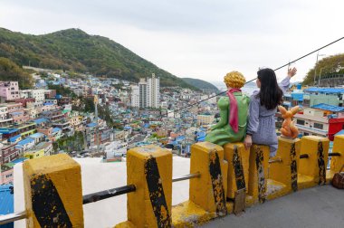 Busan, Güney Kore - Nisan 2019: Gamcheon Kültür Köyü'nü ziyaret eden turistler, Güney Kore'nin Busan ilçesindeki sahil dağının yamacında duvar resimleri ve heykellerle süslenmiş canlı boyalı evleri ile ünlü cazibe merkezi