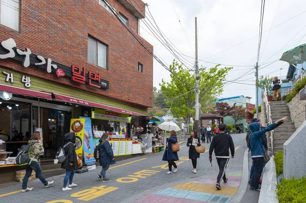 Busan, Coreia do Sul - abril de 2019: Turistas visitam Gamcheon Culture Village, famosa atração com casas vibrantemente pintadas decoradas com murais e esculturas na encosta da montanha costeira em Busan, Coreia do Sul — Fotografia de Stock