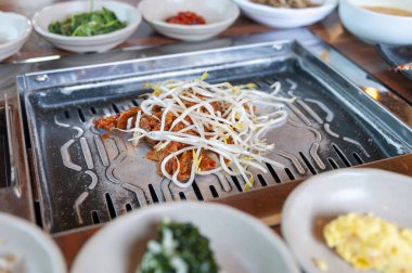 Izgara marine domuz kimchi Kore'de geleneksel Kore mutfağı restoranda sebze ve baharat sosları çeşitli yan yemekleri ile yenen fasulye filizi ile tepesinde