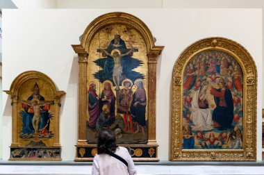 Floransa, İtalya - Ekim 2019: Galleria dell 'Accademia di Firenze' yi (Floransa Akademisi Galerisi) ziyaret eden İtalyan ressamların Kutsal Üçlü temalı üç tablosuna bakmaktadır.