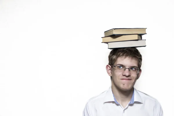 Ein junger Mann mit Brille und weißem Hemd mit Büchern auf dem Kopf. — Stockfoto