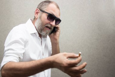 adam elinde bir sigara ile cep telefonu konuşuyor