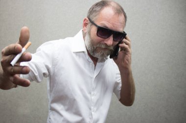 adam elinde bir sigara ile cep telefonu konuşuyor