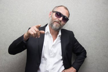 gözlüklü ve sakallı bir ceketli acımasız bir adam telefona bakıyor..