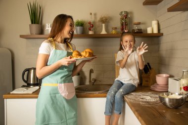 anne ve kızı mutfakta oynuyorlar, unla oynuyorlar.